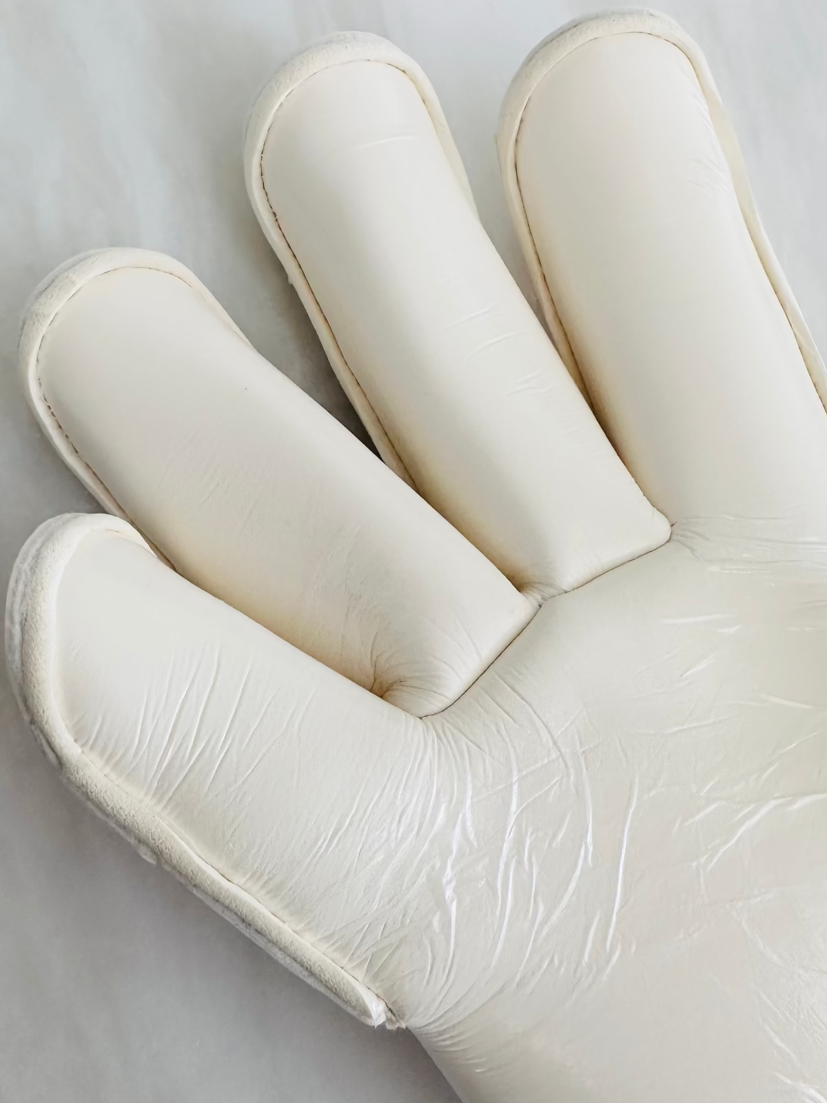 A close-up of a Tee3 Goalkeeping roll finger glove with white contact latex 