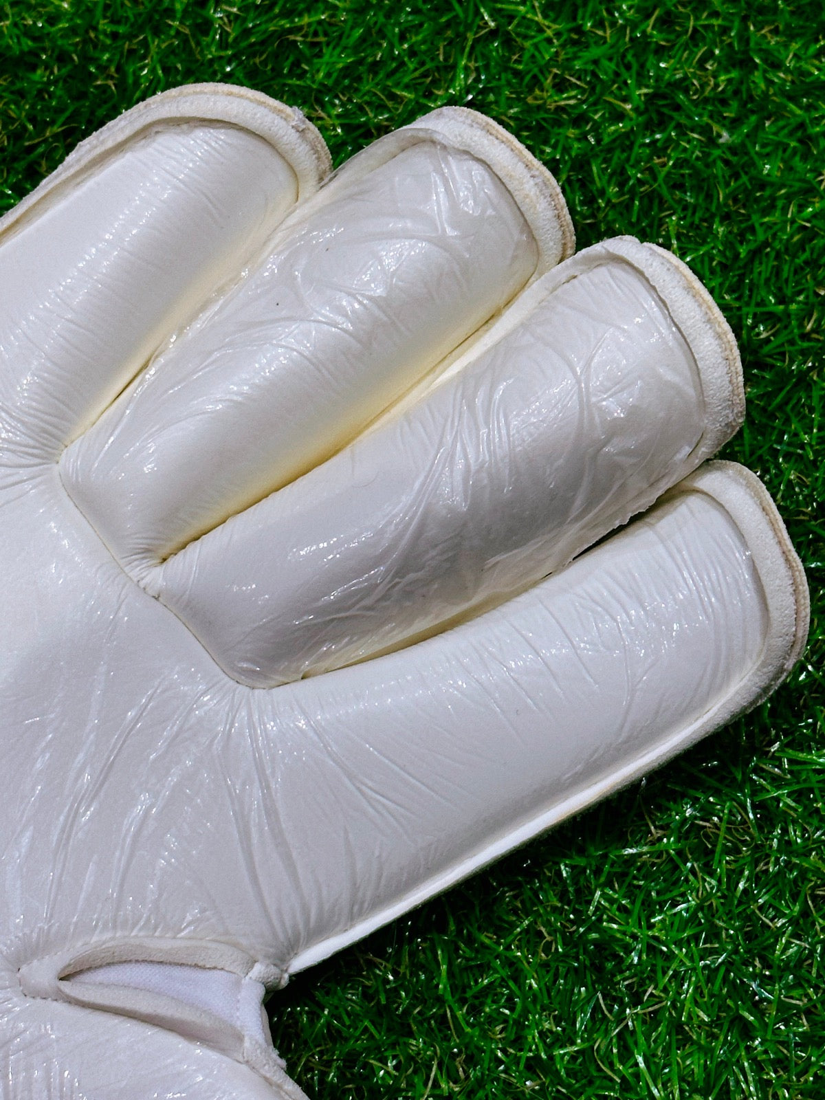 A white roll finger goalkeeping glove with a double wrap strap and 4mm German contact latex worn by professional goalkeepers
