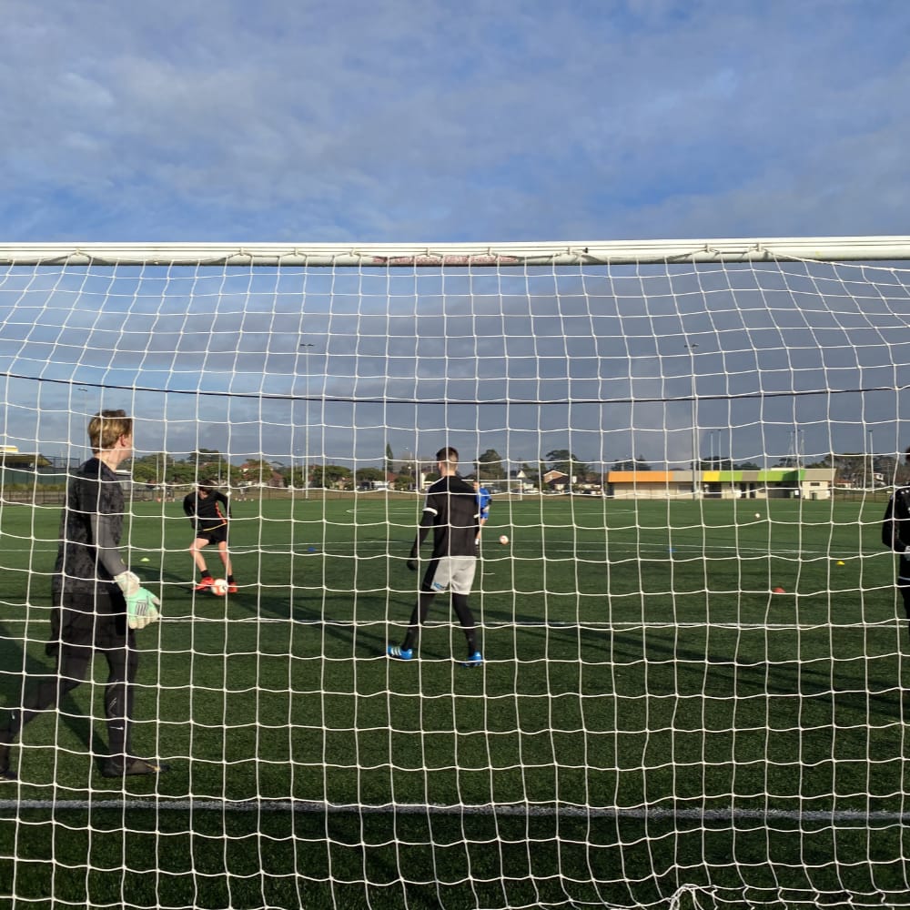 Goalkeeper training session with multiple keepers in full sized goal