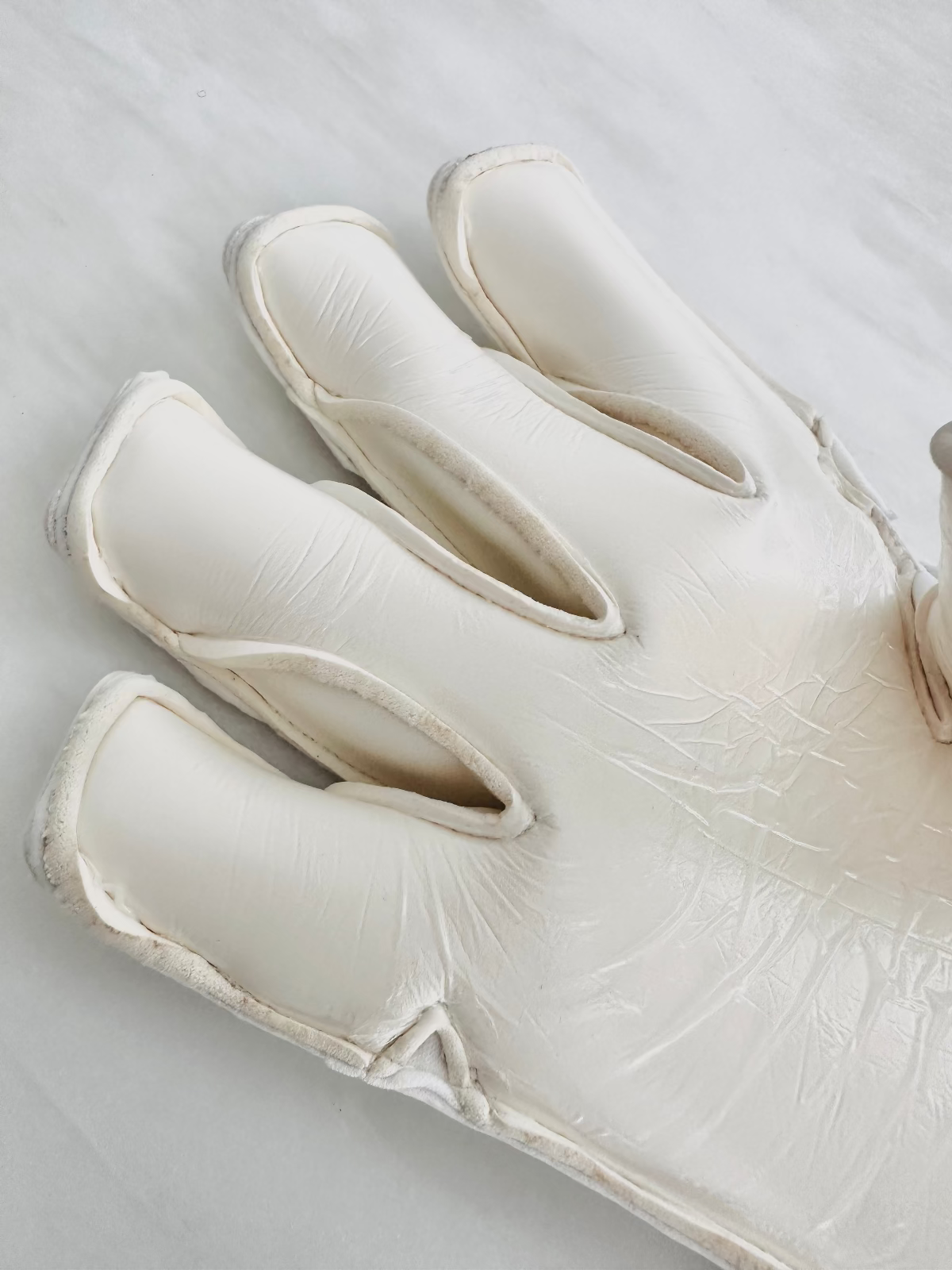 The palm of professional white Tee3 goalkeeping goalkeeper gloves photographed on a light neutral background. 