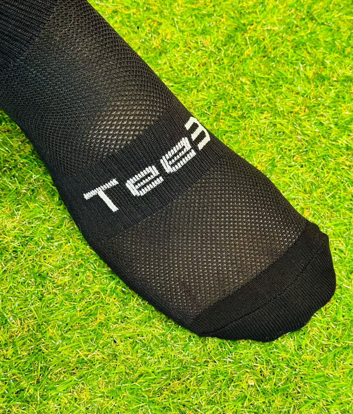 A pair of black Tee3 Goalkeeping sports grip socks with advanced grip technology, displayed on a grass surface.