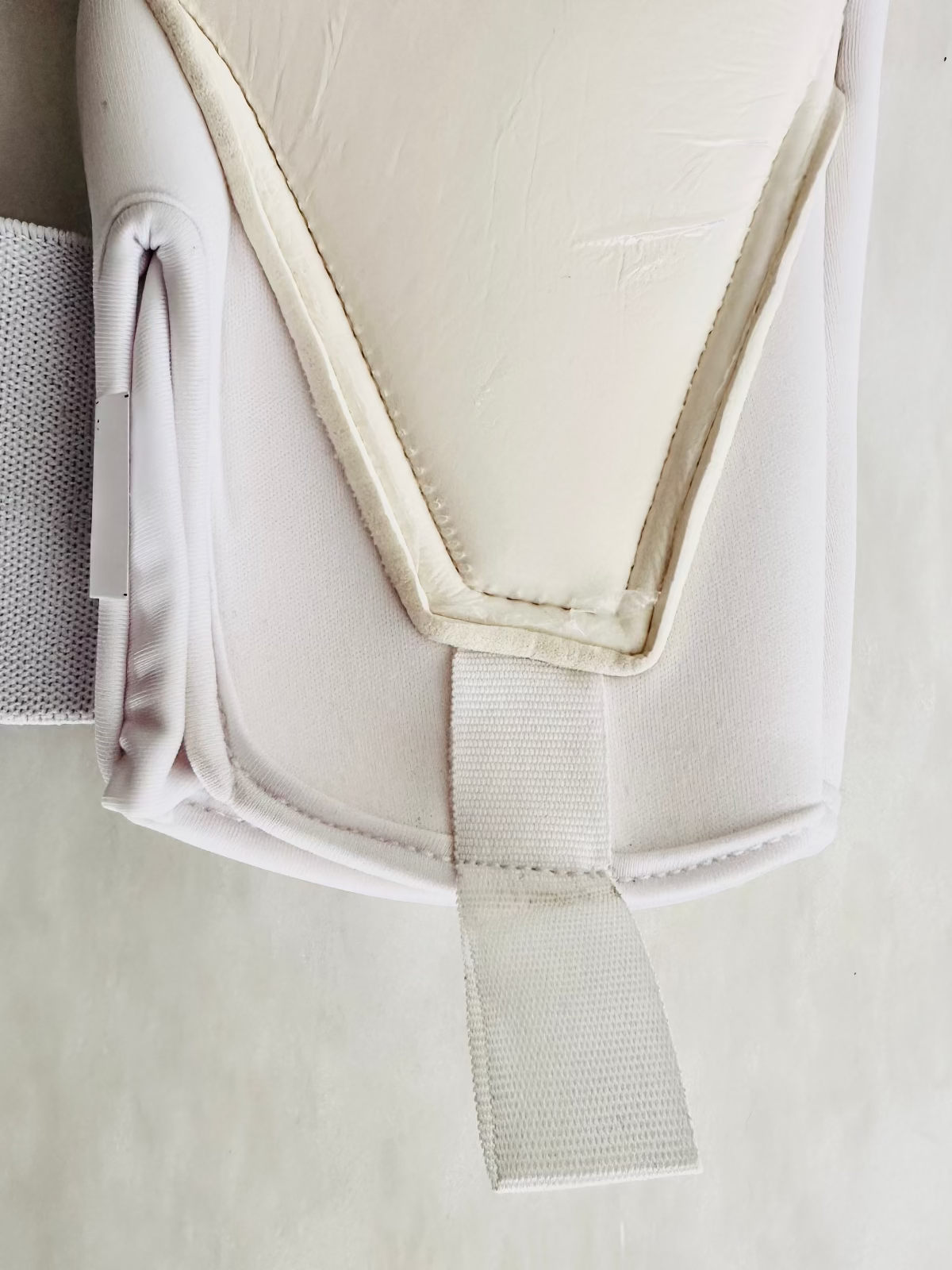 A close-up of a white TEE-3 professional goalkeeping brand wrist entry minimalist goalkeeper glove with pink and white graphic accents, made from neoprene with specific accents and details. There is an easy entry at the beginning of the tunnel 